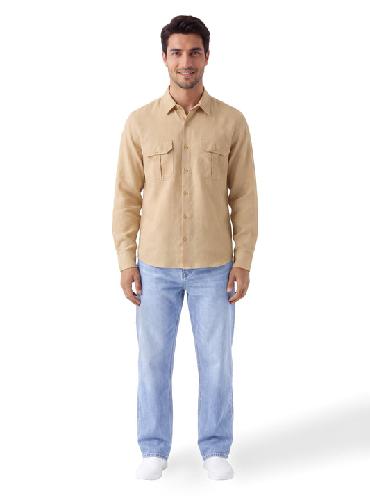 A man modeling a light beige long-sleeve button-up shirt with two chest pockets, paired with light blue jeans and white sneakers, against a plain white background.