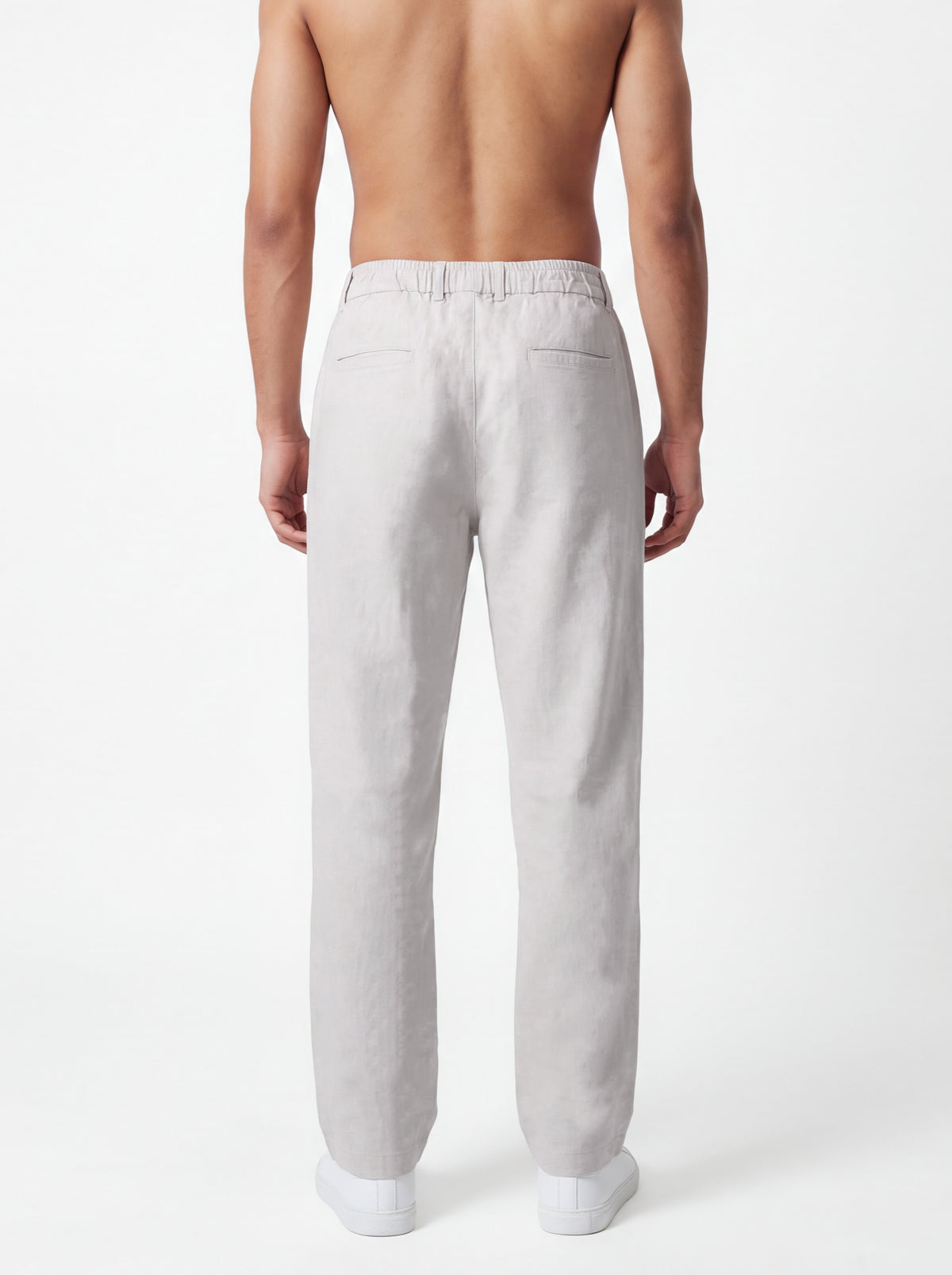 A man shown from the back wearing light gray linen trousers, photographed against a clean white studio background.