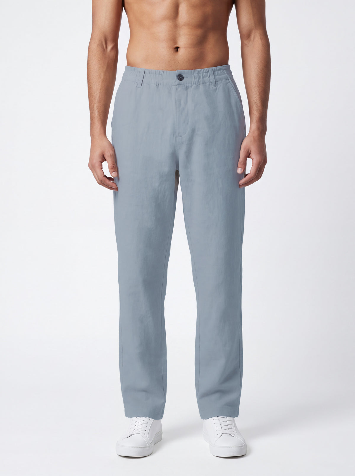 A man wearing light blue straight-leg trousers and white sneakers, shown from the waist down against a plain white studio background.