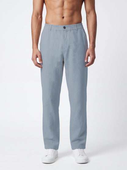 A man wearing light blue straight-leg trousers and white sneakers, shown from the waist down against a plain white studio background.