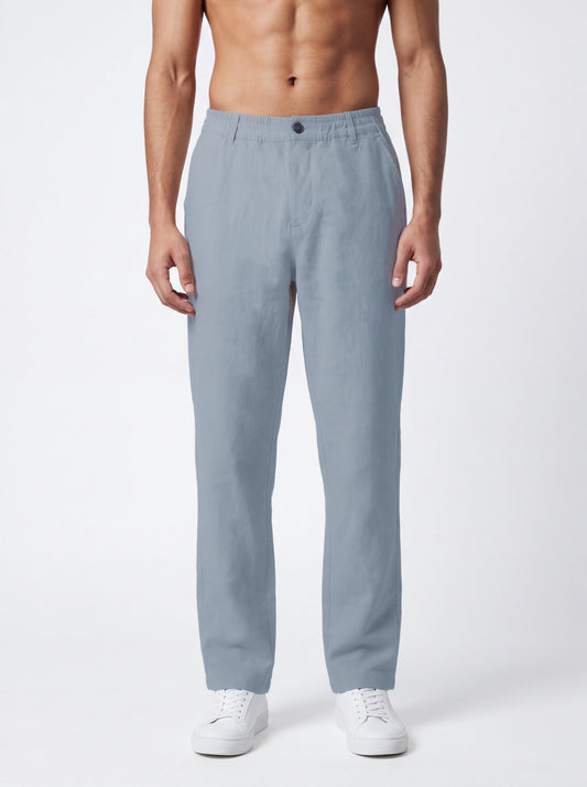 A man wearing light blue straight-leg trousers and white sneakers, shown from the waist down against a plain white studio background.