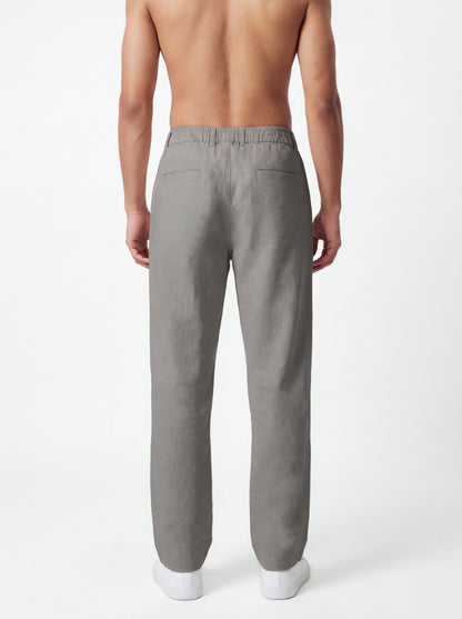 A man shown from the back wearing light gray linen trousers, photographed against a clean white studio background.