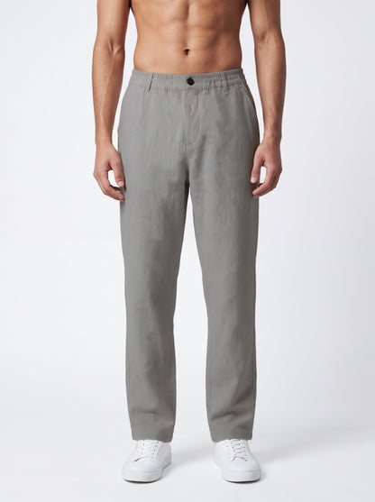 A man wearing light gray straight-leg trousers and white sneakers, standing against a plain light gray studio background.