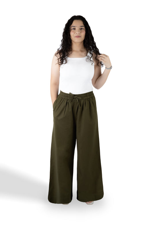 A woman modeling a pair of wide-leg olive green pants with a drawstring waist, paired with a white tank top, against a plain white background.