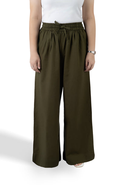 A model wearing olive green wide-leg drawstring pants with a white sleeveless top, shown from the chest down against a white studio background.