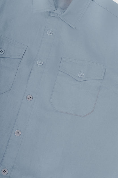 Close-up of a light blue button-down shirt showing the collar, front button placket, and left chest pocket.