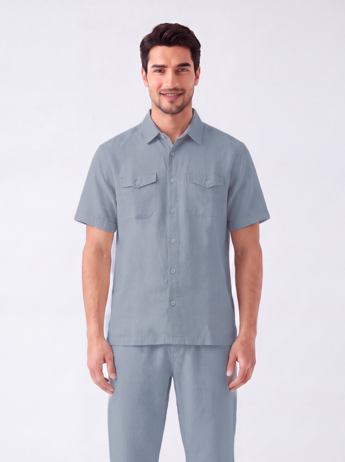 A man modeling a light blue short-sleeve button-up shirt and matching trousers against a plain light gray studio background.