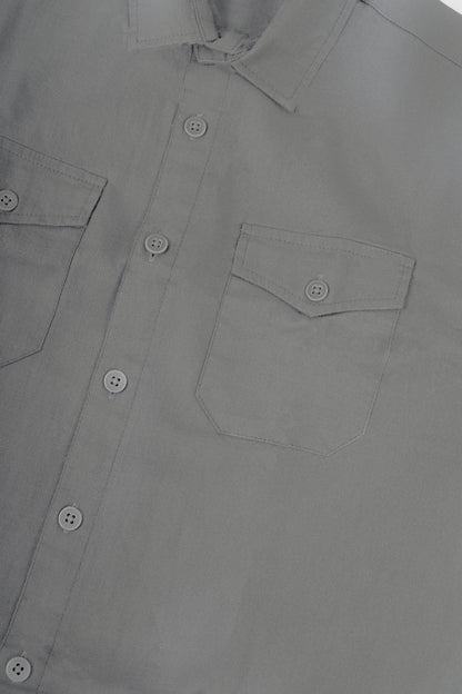 Close-up of a light gray button-down shirt showing the collar, front button placket, and left chest pocket with a button flap.