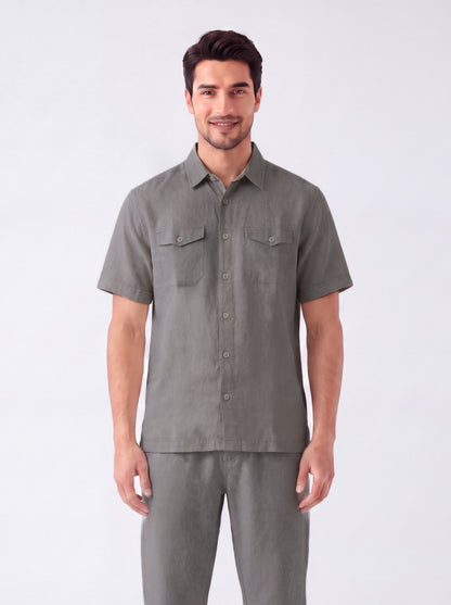 A man modeling a short-sleeve button-up shirt and matching trousers in a solid gray color, photographed against a clean white studio background.