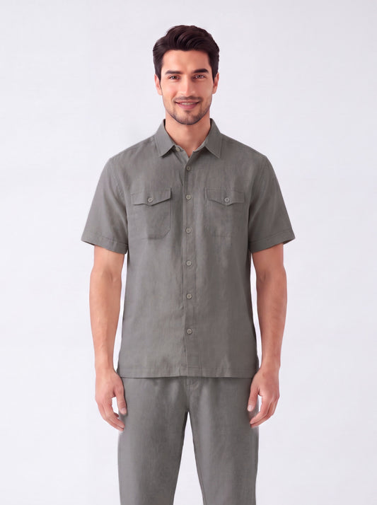 A man modeling a short-sleeve button-up shirt and matching trousers in a solid gray color, photographed against a clean white studio background.