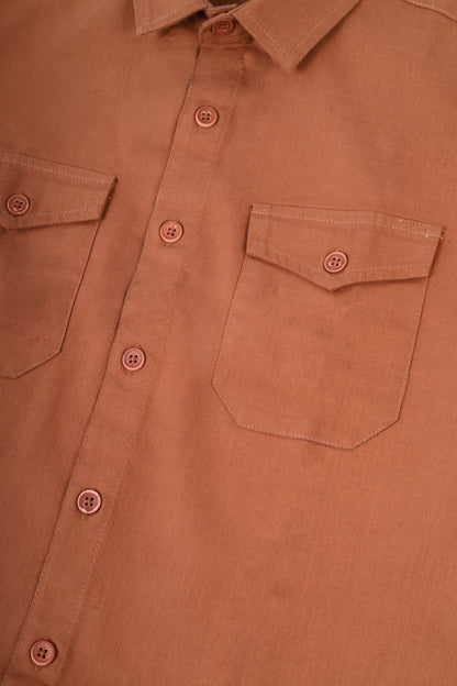 Close-up of a terracotta-colored button-down shirt showing the chest pocket, button closure, and collar.