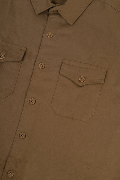 Close-up of a brown button-up shirt showing the chest pocket, button details, and textured fabric.