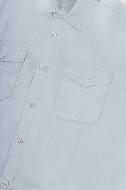 Close-up of a light blue button-down shirt showing the collar, front button placket, and chest pocket details.
