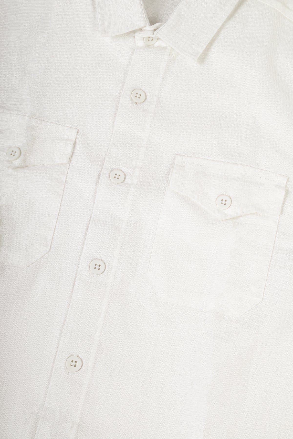 Close-up of a white long-sleeve button-up shirt showing the collar, front buttons, and left chest pocket.