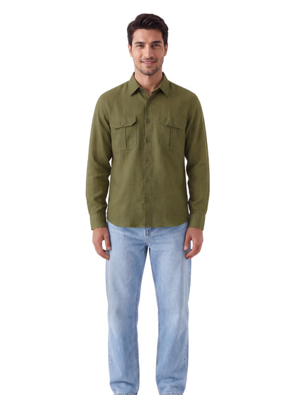 A man wearing an olive green long-sleeve button-up shirt with two chest pockets and light blue jeans, standing against a plain white background.