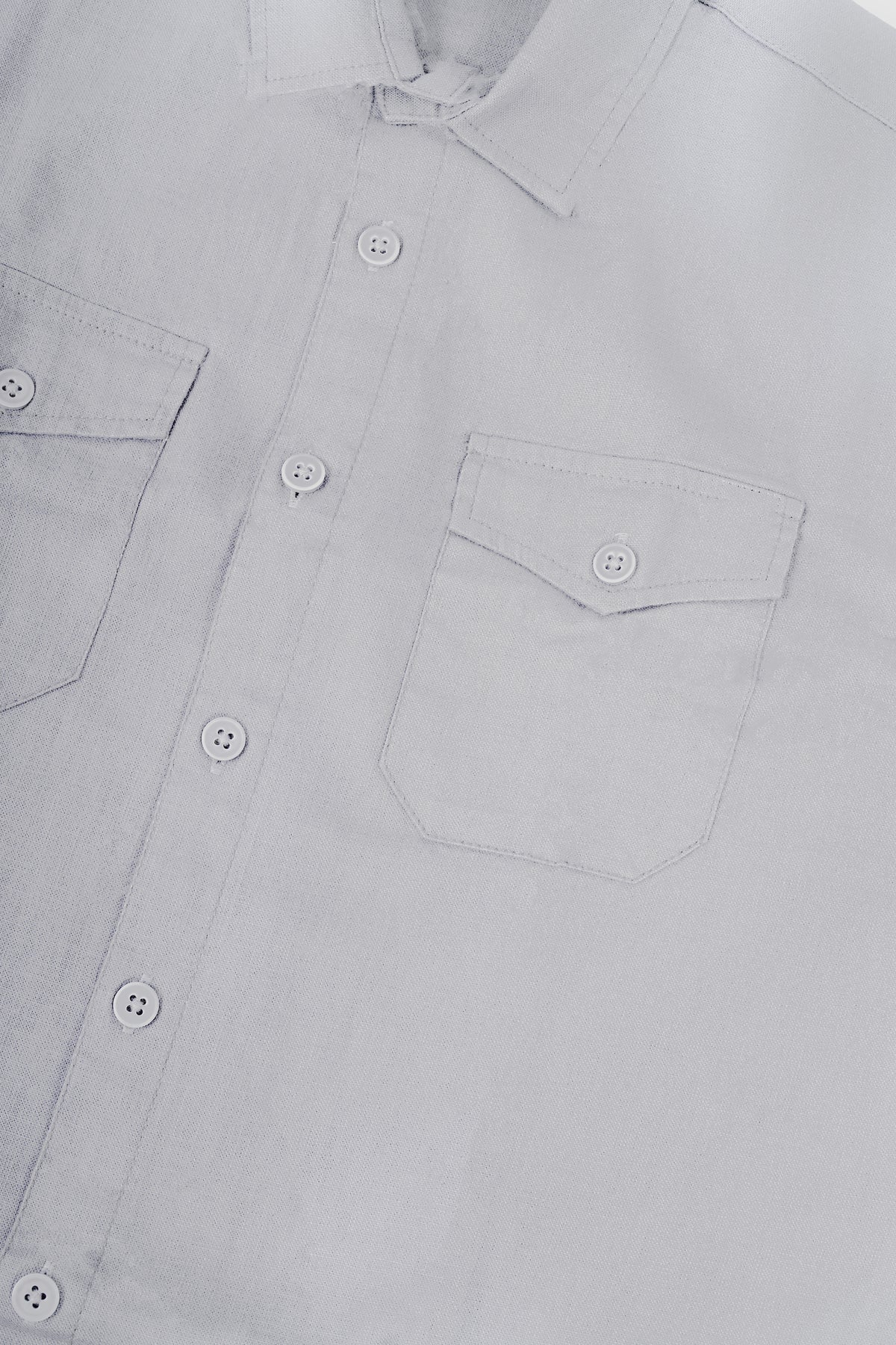 Close-up of a light gray or off-white button-down shirt showing the collar, front button placket, and two buttoned chest pockets.