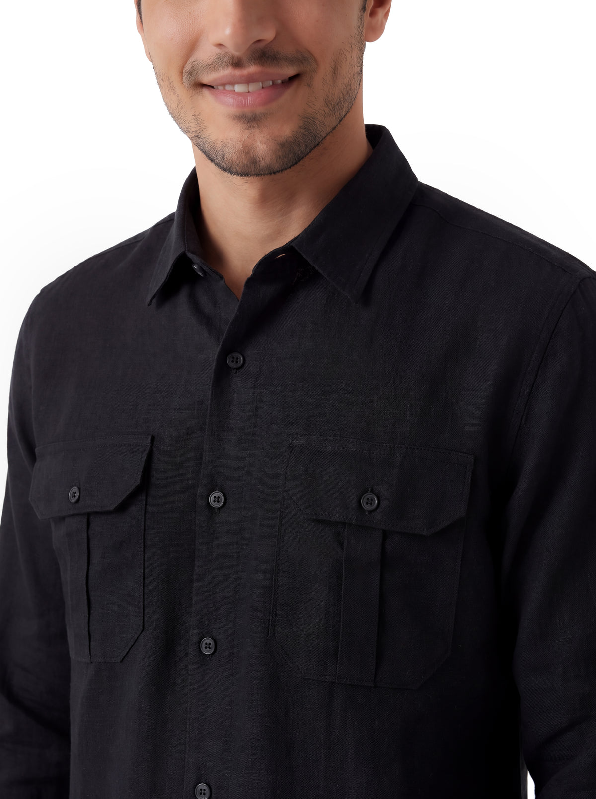 A close-up of a man wearing a black long-sleeve button-up shirt with two buttoned chest pockets, photographed against a plain white background.