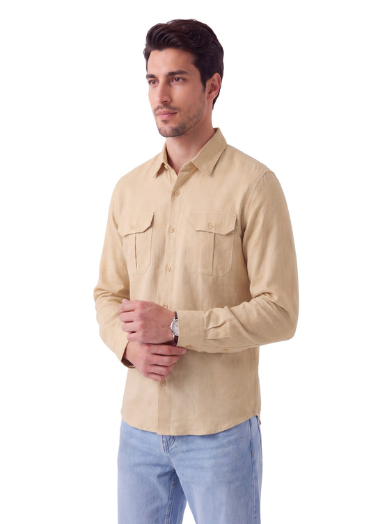 A man wearing a light beige long-sleeve button-down shirt with two chest pockets and light blue jeans, standing against a plain white background.