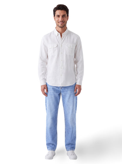 A man wearing a white long-sleeve button-up shirt and light blue jeans, standing against a plain white background.