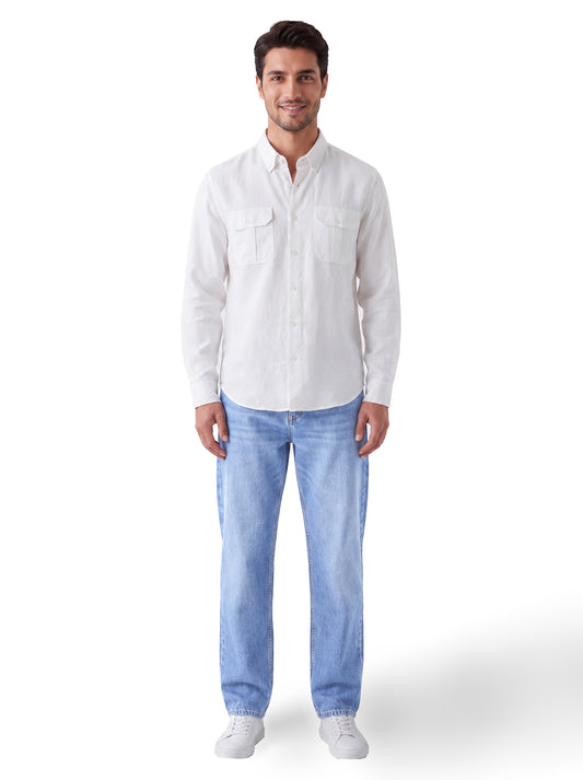 A man wearing a white long-sleeve button-up shirt and light blue jeans, standing against a plain white background.