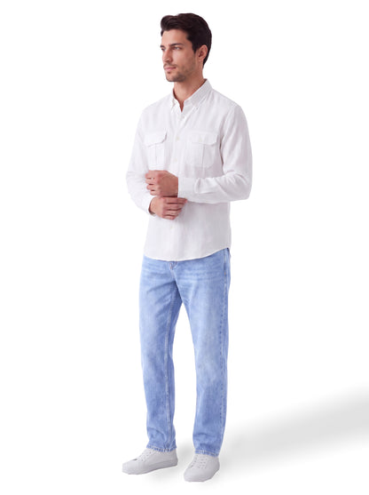 A man wearing a white long-sleeve button-up shirt, light blue jeans, and white sneakers, standing against a plain white background.