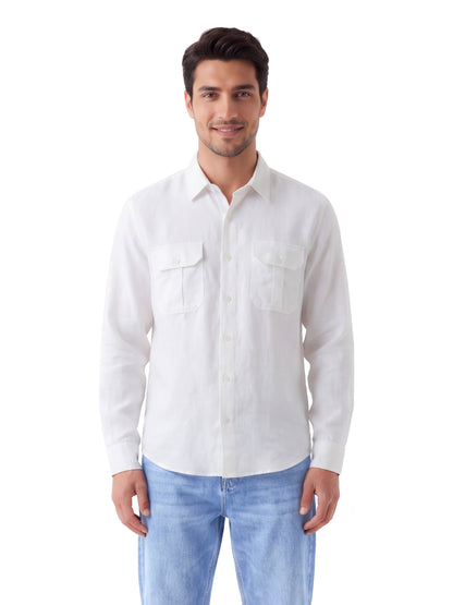 A man wearing a white long-sleeve button-up shirt with two chest pockets and light blue jeans, standing against a plain white background.