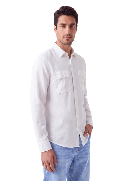A man wearing a white long-sleeve linen button-down shirt with two chest pockets and light blue jeans, standing against a solid white background.