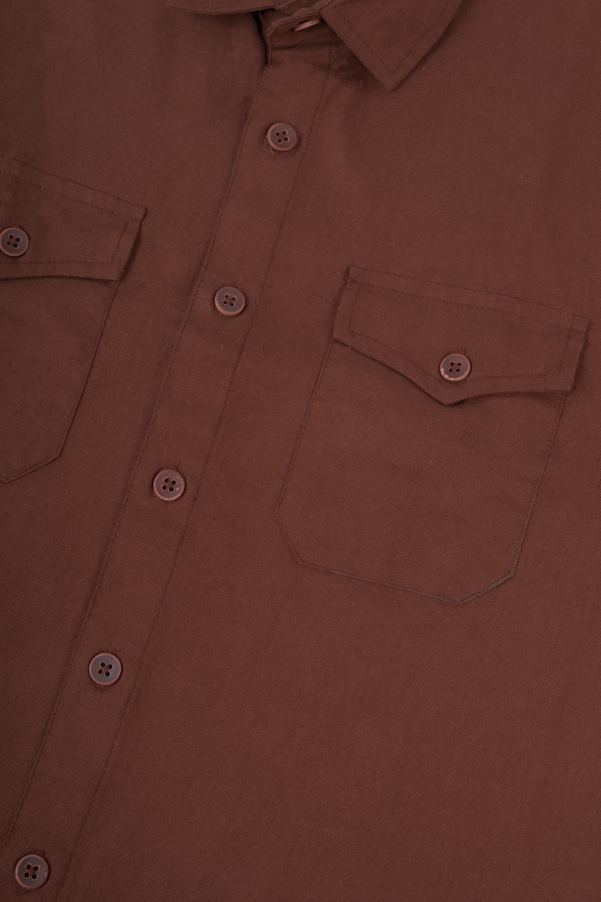 Close-up of a brown button-up shirt showing the chest pocket, button closure, and fabric texture.