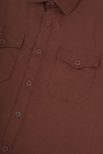 Close-up of a brown button-up shirt showing the chest pocket, button closure, and fabric texture.