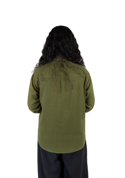 A person viewed from the back wearing an olive green long-sleeve shirt and dark pants, standing against a plain white background.