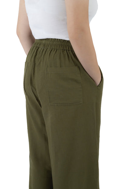 A person wearing olive green wide-leg trousers with an elastic waistband and a side pocket, paired with a white sleeveless top, shown from a rear three-quarter angle against a white background.
