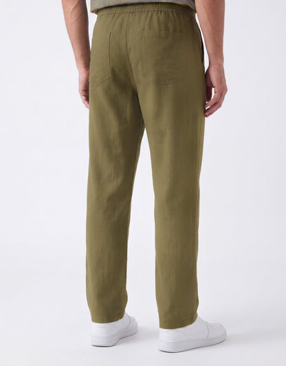 A person shown from the back wearing olive green trousers and white sneakers against a clean white studio background.