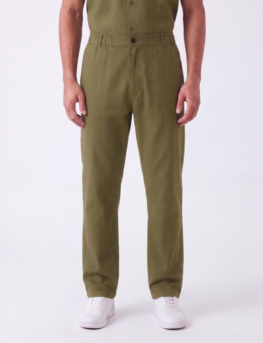 A person wearing olive green straight-leg work pants with white sneakers, shown from the chest down against a plain white studio background.