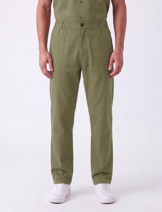 A person wearing olive green straight-leg work pants with white sneakers, shown from the waist down against a plain white studio background.