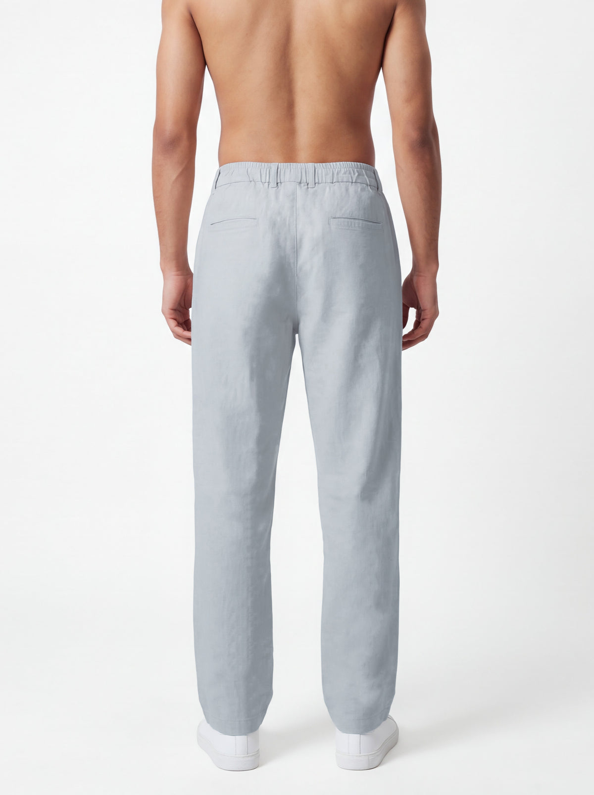 A man shown from the back wearing light gray linen trousers, photographed against a clean white studio background.