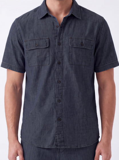 A man wearing a dark charcoal gray short-sleeve button-up shirt with two chest flap pockets, shown from the neck down against a plain white background.