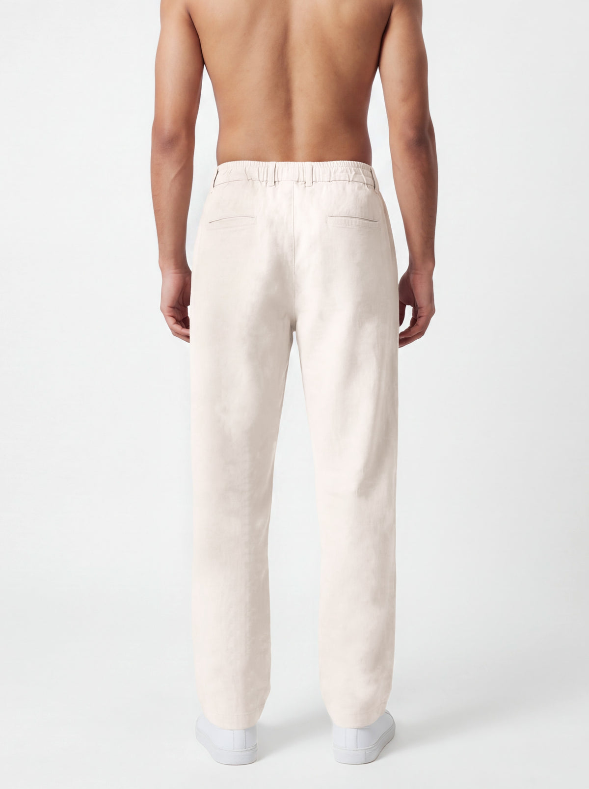 A man shown from the back wearing light cream-colored linen trousers, photographed against a clean white studio background.