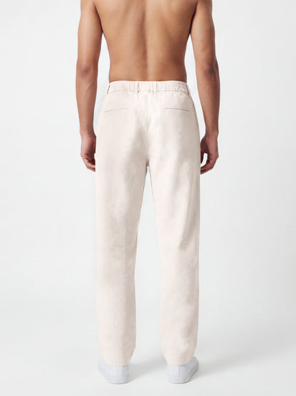 A man shown from the back wearing light cream-colored linen trousers, photographed against a clean white studio background.