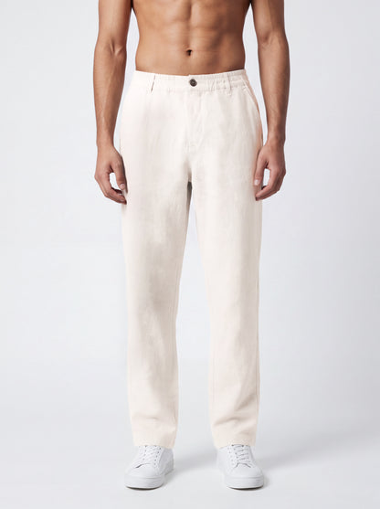 A man wearing off-white linen trousers and white sneakers, shown from the waist down against a light gray studio background.