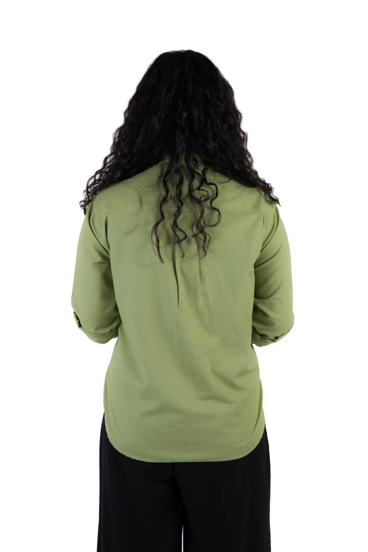 A person viewed from the back wearing a sage green long-sleeve button-up shirt and black pants, isolated on a white background.