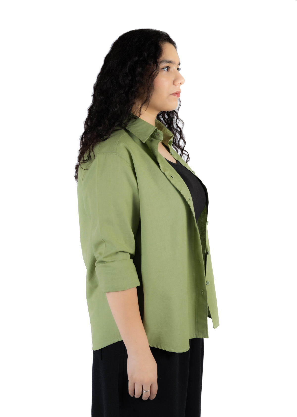A woman shown in side profile wearing an olive green button-up shirt over a black top and black pants, photographed against a plain white studio background.