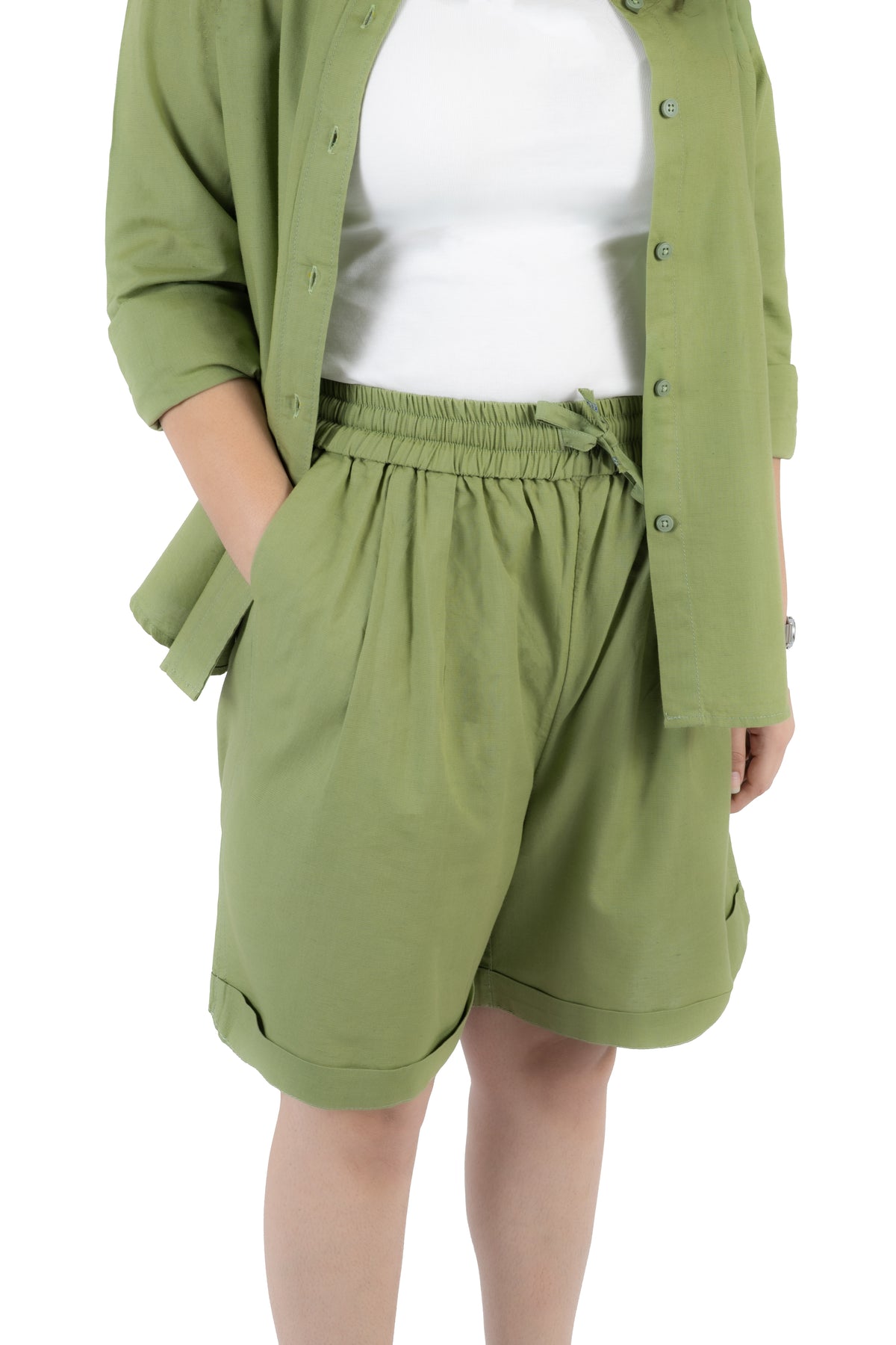 A person wearing olive green drawstring shorts with a white sleeveless top, shown from the chest to the knees against a plain white background.