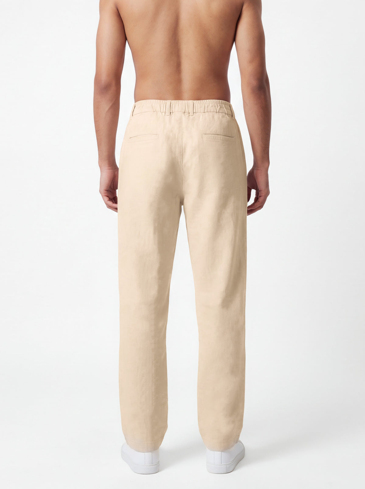A man shown from the back wearing light beige linen trousers, photographed against a clean white studio background.