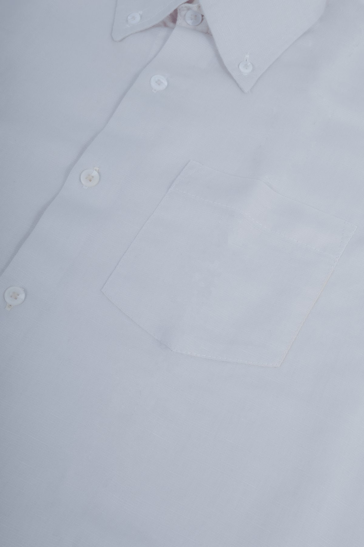 Close-up of a white long-sleeve button-down shirt showing the collar, front buttons, and chest pocket.