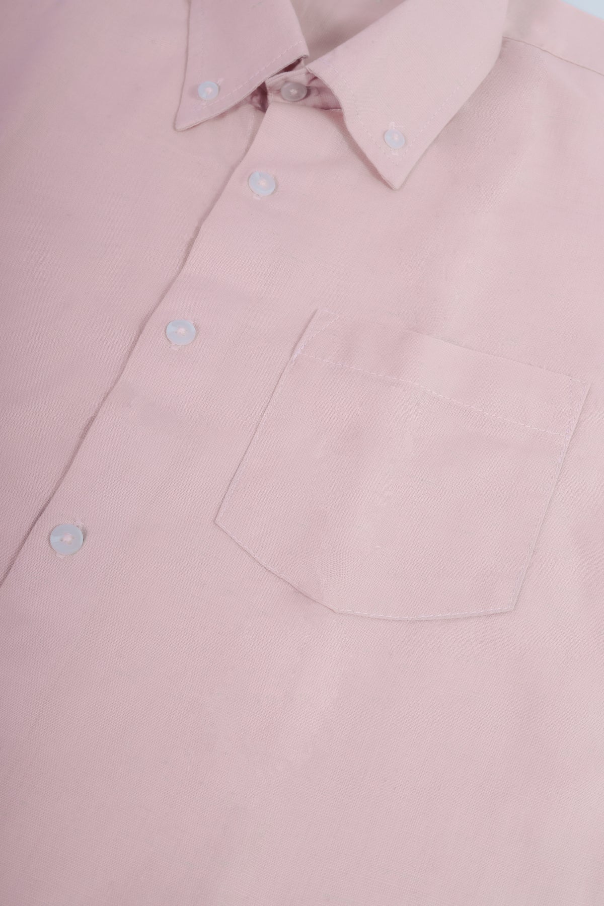 A closeup of a pastel pink  button-down shirt.