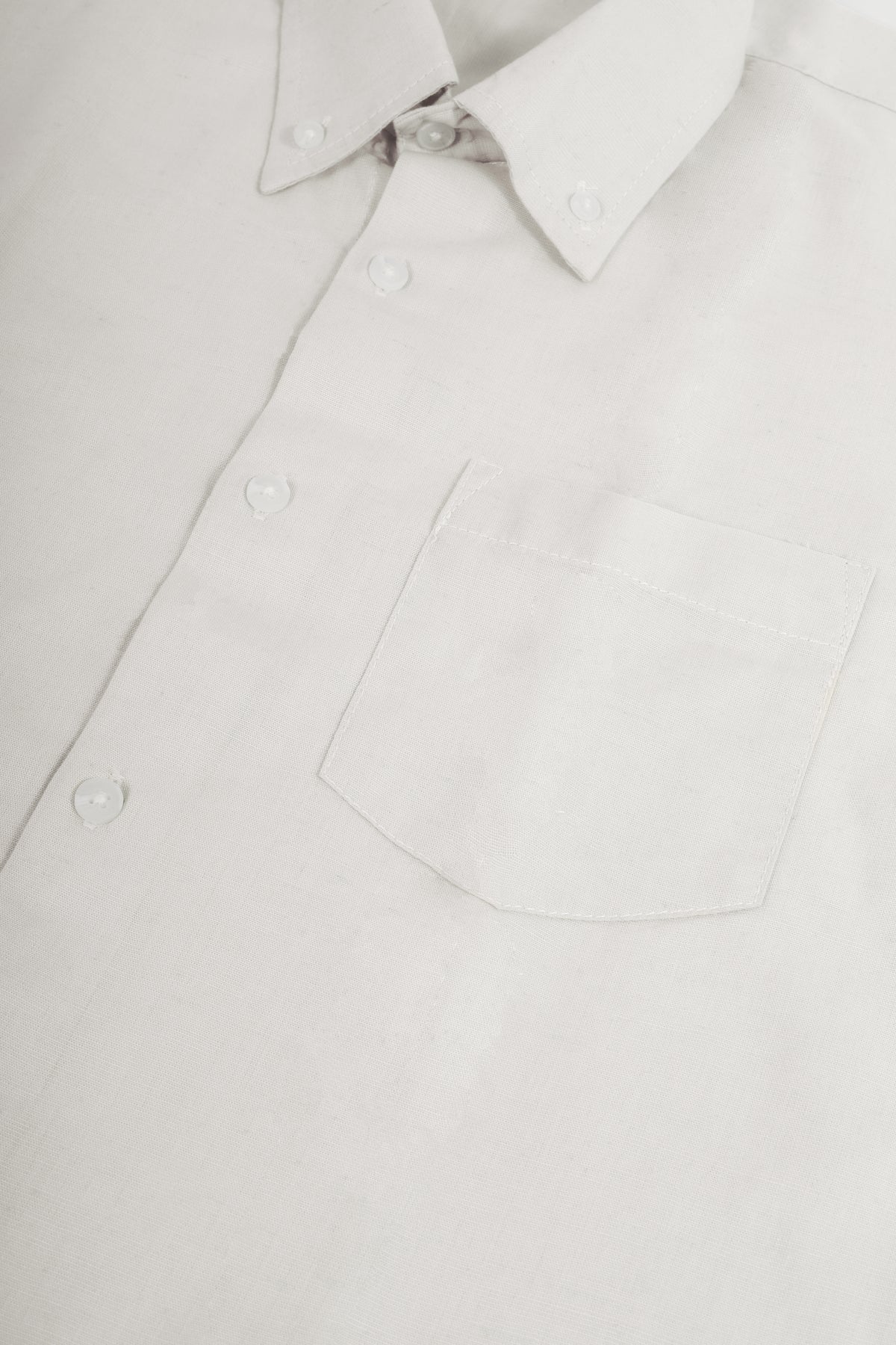 Close-up of a white long-sleeve button-down shirt showing the collar, front buttons, and chest pocket.