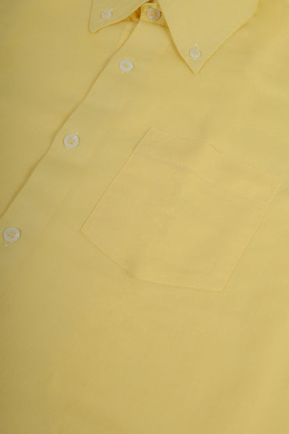 A close-up of a light yellow long-sleeve button-down shirt, showing the collar, white buttons, and a chest pocket.