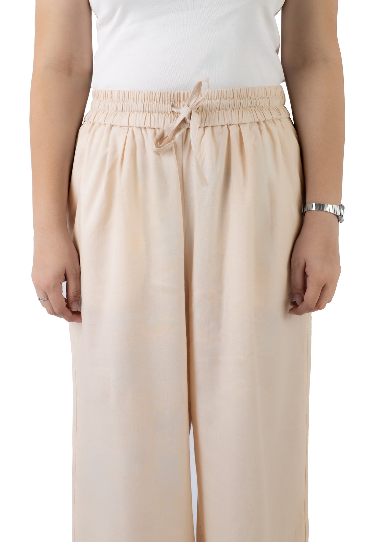A person wearing light beige wide-leg trousers with an elastic drawstring waist, paired with a white sleeveless top, shown against a plain white background.
