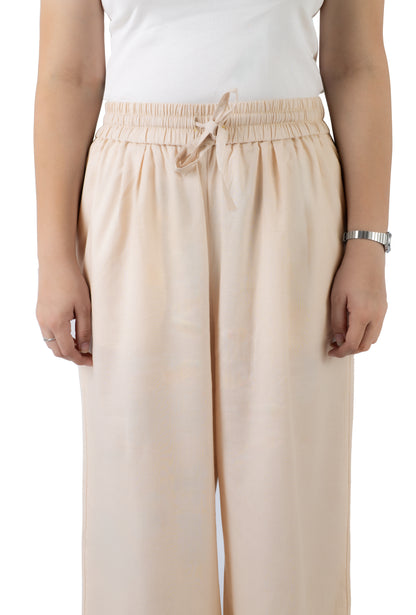 A person wearing light beige wide-leg trousers with an elastic drawstring waist, paired with a white sleeveless top, shown against a plain white background.
