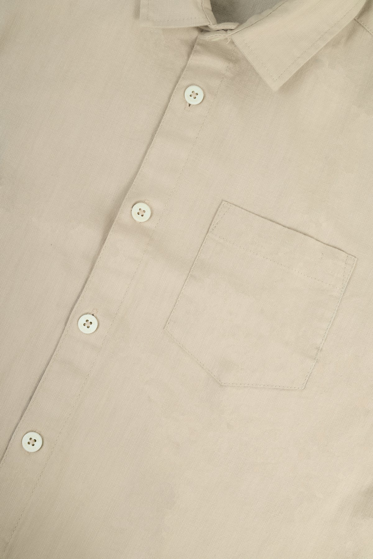 Close-up of a light beige button-down shirt showing the collar, front buttons, and chest pocket.